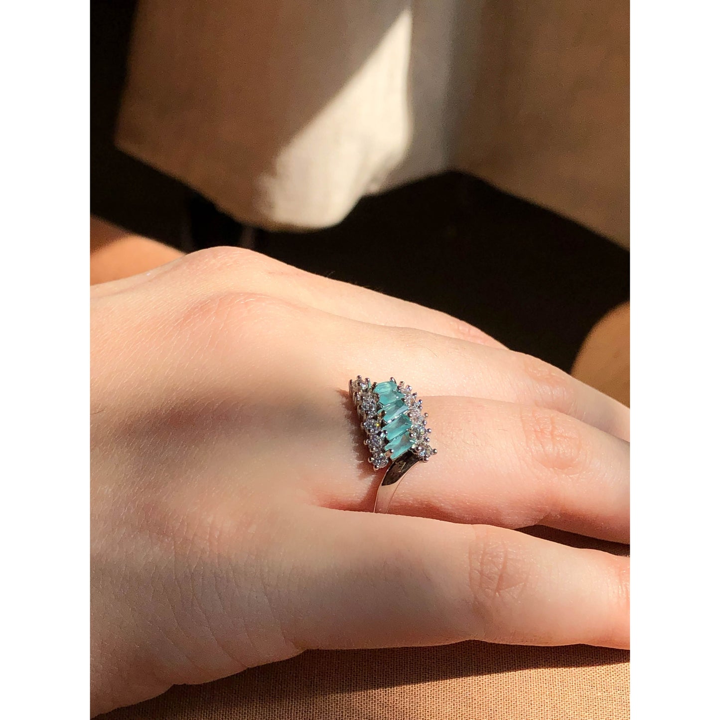A close-up of a slender ring band completely covered in small, sparkling clear cubic zirconia stones, displayed on a reflective surface.