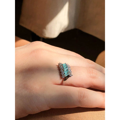 A close-up of a slender ring band completely covered in small, sparkling clear cubic zirconia stones, displayed on a reflective surface.