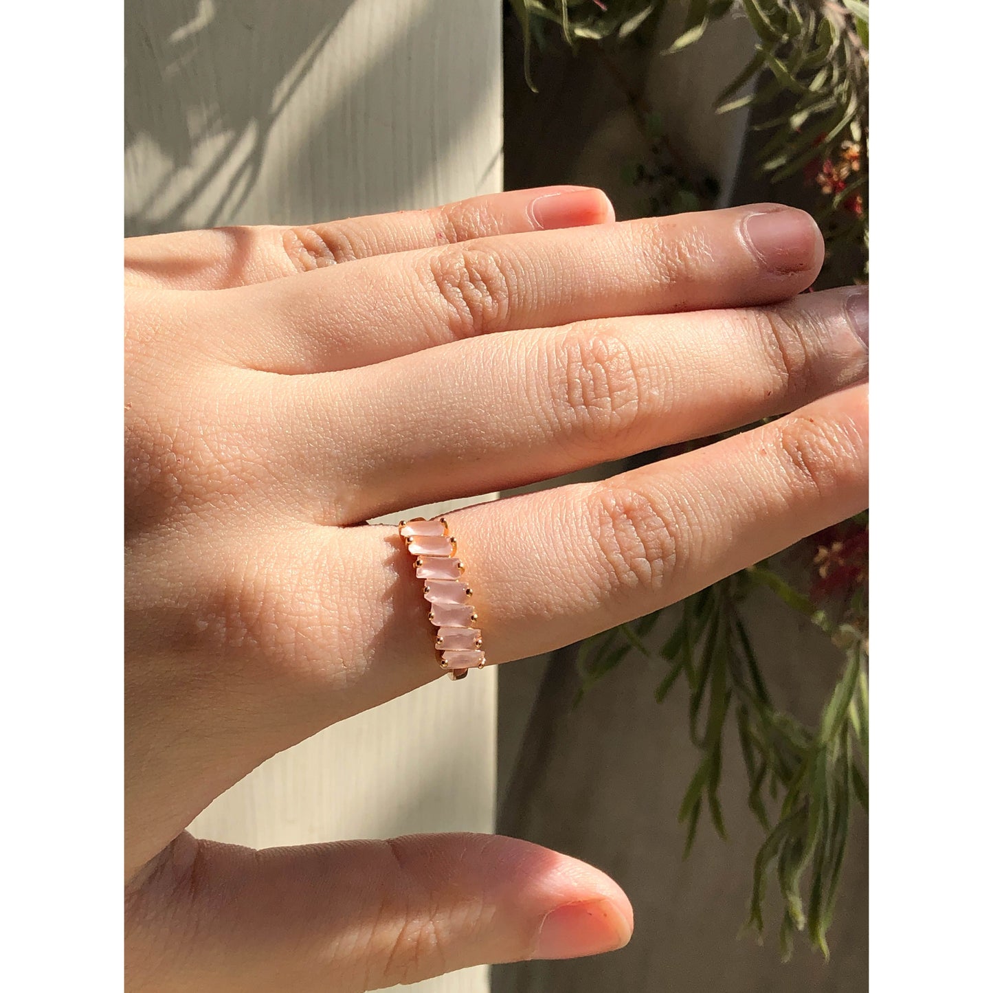 A close-up of a sparkling silver-tone ring featuring a large, rectangular emerald-cut clear stone in the center, flanked by smaller clear round stones set along the band.