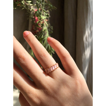 A close-up of a sparkling silver-tone ring featuring a large, rectangular emerald-cut clear stone in the center, flanked by smaller clear round stones set along the band.