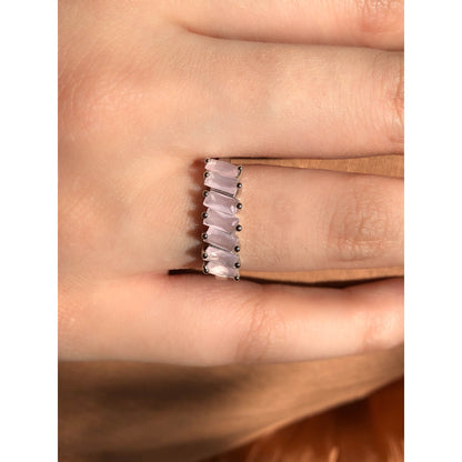 A close-up of a sparkling silver-tone ring featuring a large, rectangular emerald-cut clear stone in the center, flanked by smaller clear round stones set along the band.