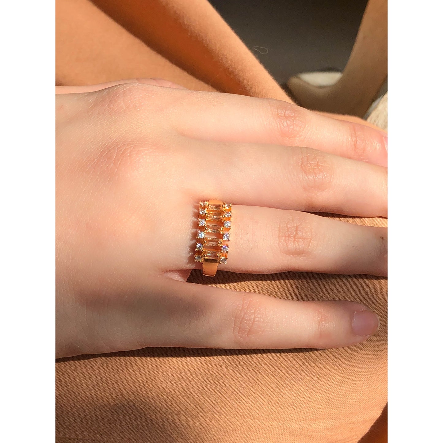 A close-up of a glittering ring featuring a large central clear stone and a band entirely covered in multiple rows of smaller clear sparkling stones.