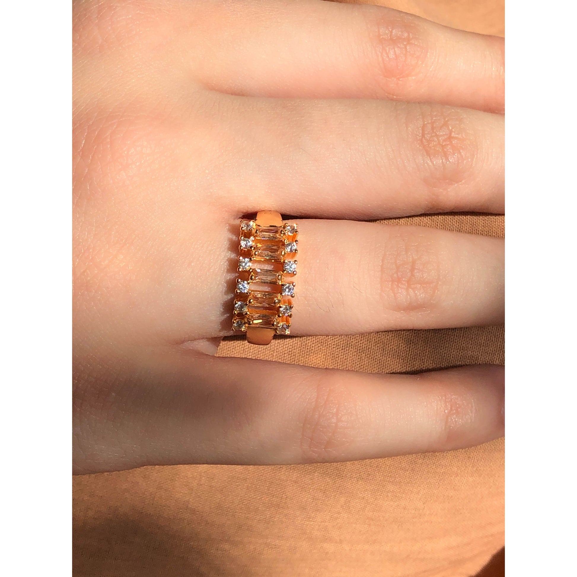 A close-up of a glittering ring featuring a large central clear stone and a band entirely covered in multiple rows of smaller clear sparkling stones.