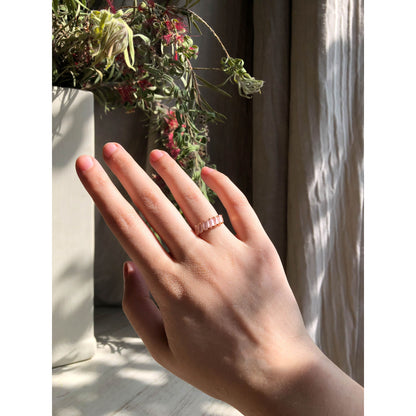 A close-up of a sparkling silver-tone ring featuring a large, rectangular emerald-cut clear stone in the center, flanked by smaller clear round stones set along the band.