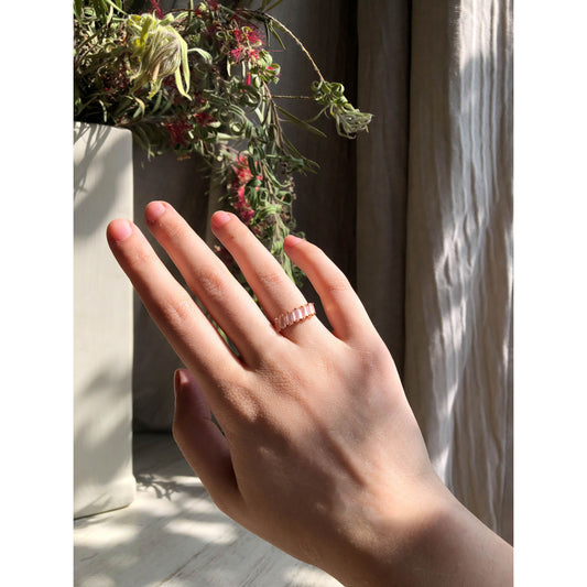 A close-up of a sparkling silver-tone ring featuring a large, rectangular emerald-cut clear stone in the center, flanked by smaller clear round stones set along the band.