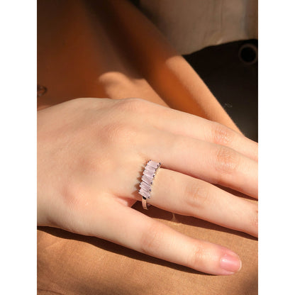 A close-up of a sparkling silver-tone ring featuring a large, rectangular emerald-cut clear stone in the center, flanked by smaller clear round stones set along the band.