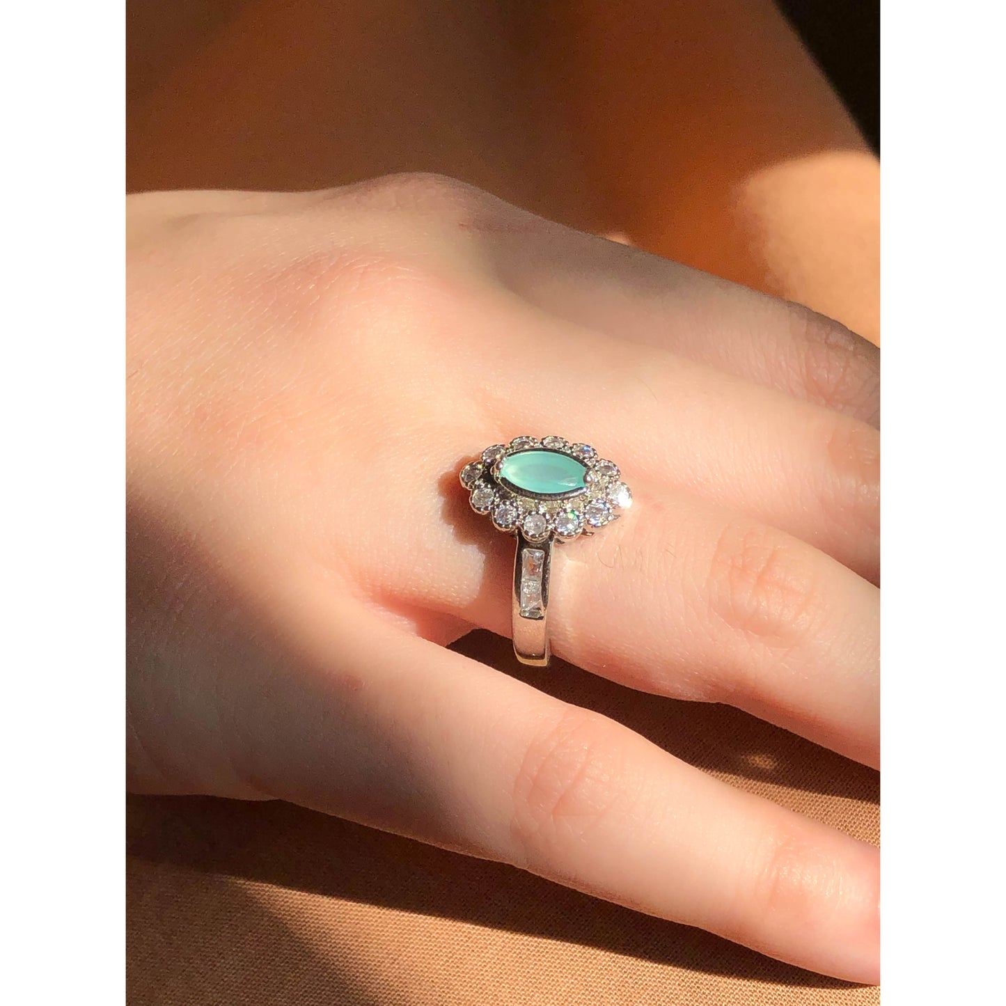 A close-up of a slender silver-tone ring featuring a single clear, faceted teardrop or oval-shaped cubic zirconia stone