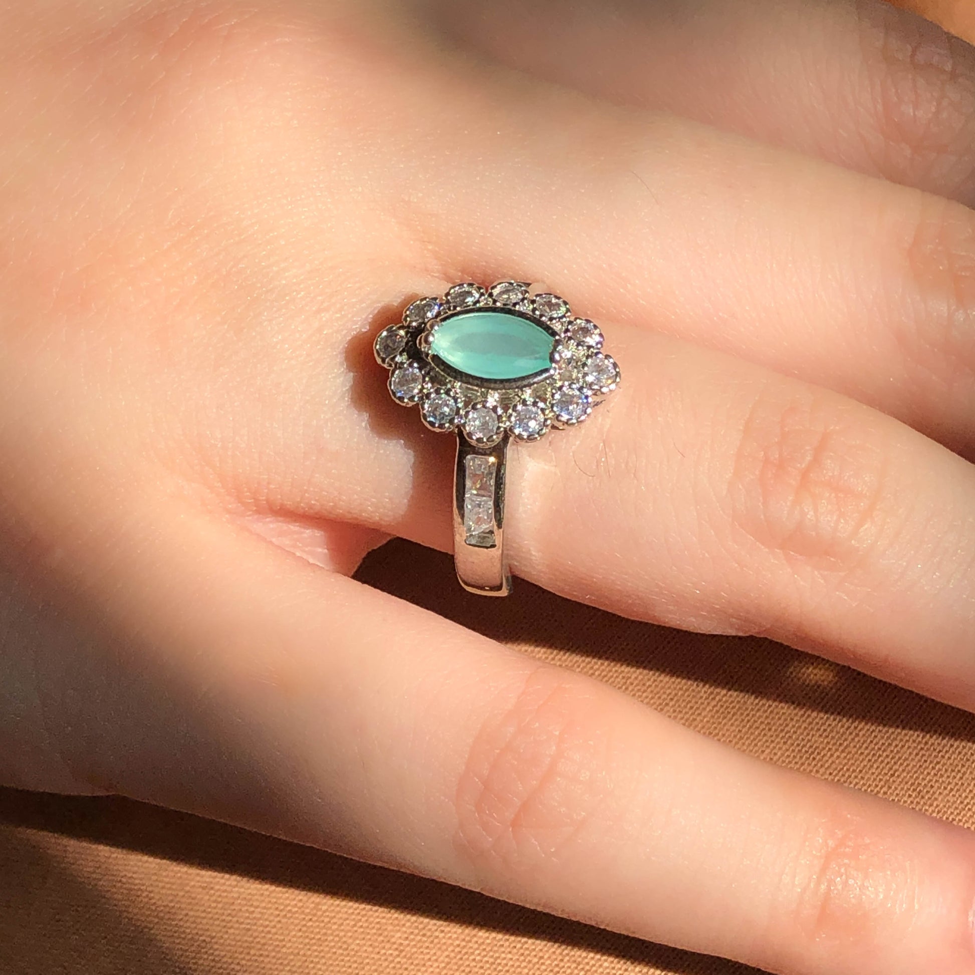 A close-up of a slender silver-tone ring featuring a single clear, faceted teardrop or oval-shaped cubic zirconia stone