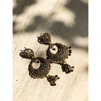 A collection of traditional jhumka earrings, featuring ornate bell shapes with intricate filigree details and various colorful accents like blue enamel or small dangling beads.