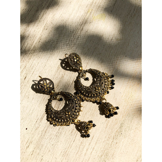 A pair of ornate silver-tone chandbali jhumka earrings featuring a crescent moon design at the top with intricate patterns and a dangling bell-shaped jhumka at the bottom.
