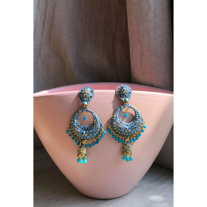 A collection of traditional jhumka earrings, featuring ornate bell shapes with intricate filigree details and various colorful accents like blue enamel or small dangling beads.