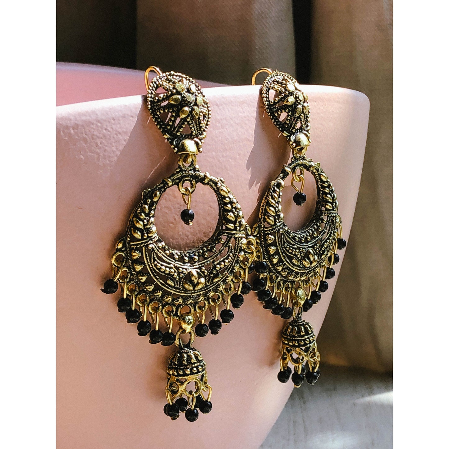 A collection of traditional jhumka earrings, featuring ornate bell shapes with intricate filigree details and various colorful accents like blue enamel or small dangling beads.