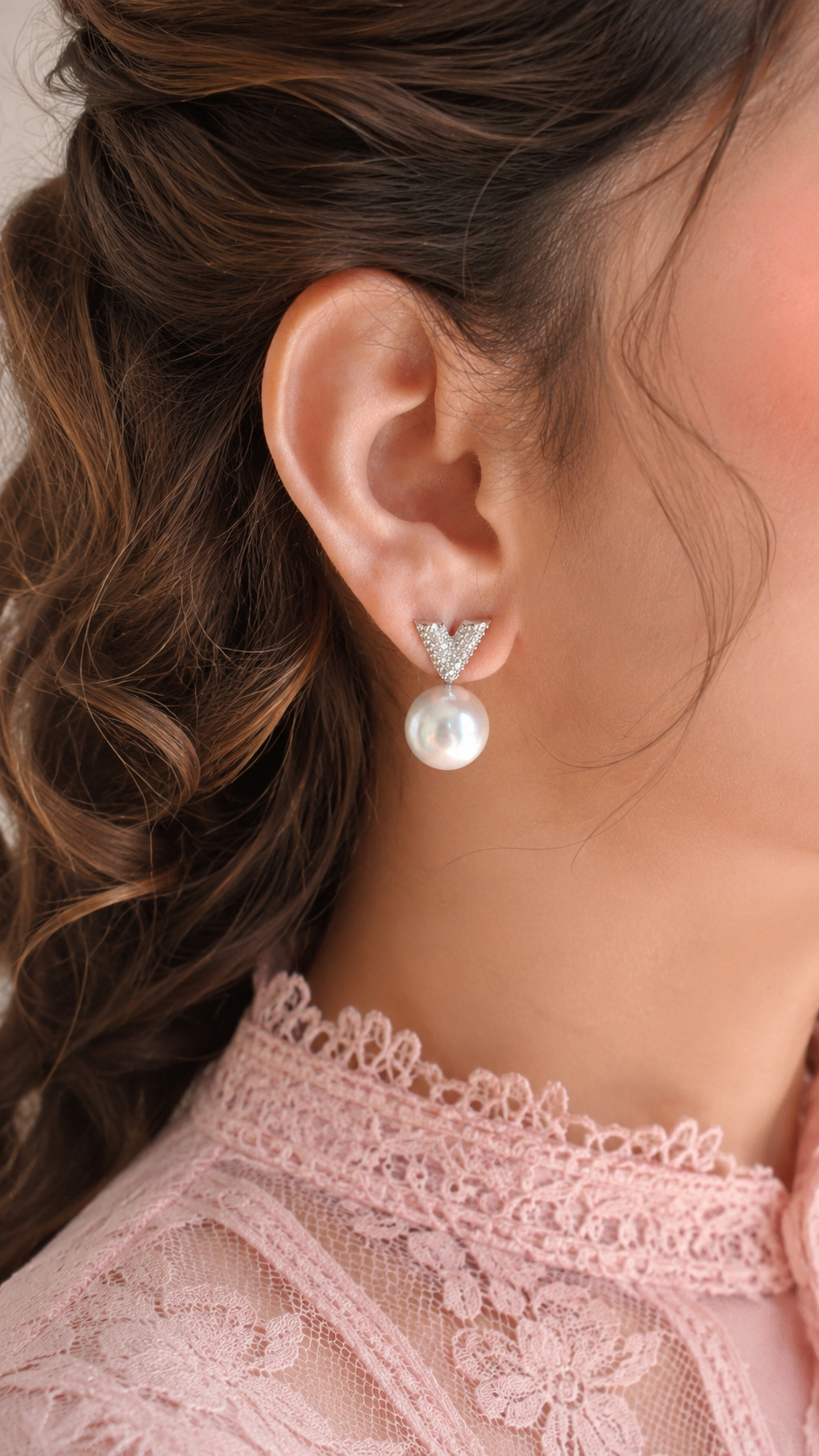 Close-up of a person wearing pearl earrings with a blurred background
