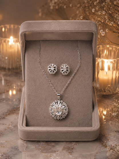 Silver floral crystal pendant necklace and matching stud earrings displayed in a premium jewellery box with intricate radiant detailing.