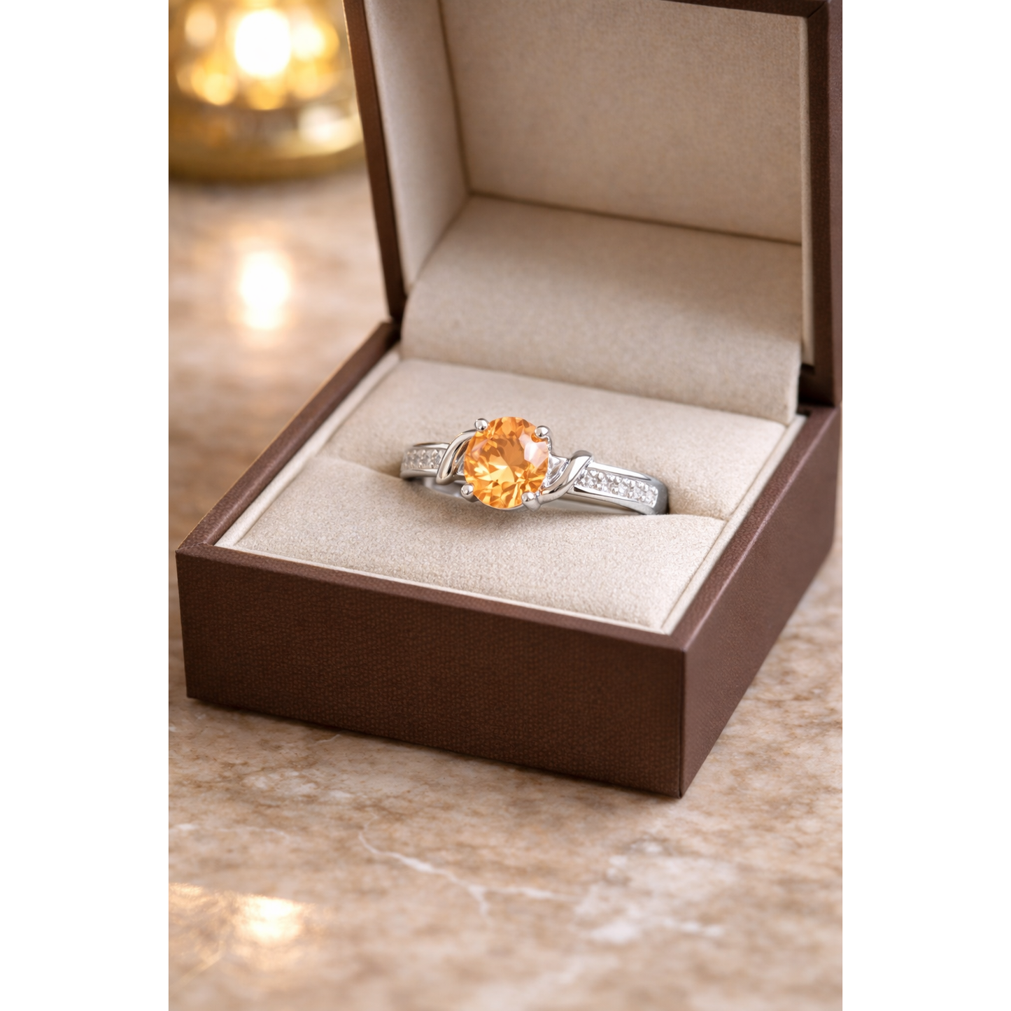 Round cut gemstone twist solitaire ring in silver champaign gem stone finish displayed inside beige luxury jewelry box
