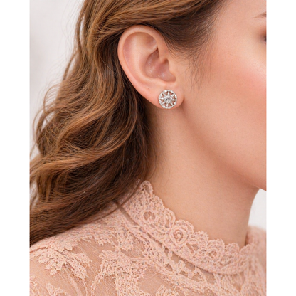 Silver circular crystal stud earrings worn on ear with geometric design close-up