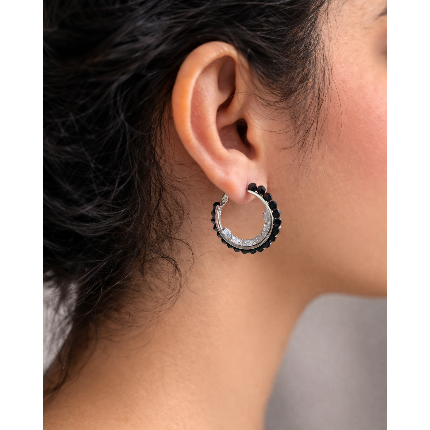 Woman wearing black beaded silver hoop earrings close up side view