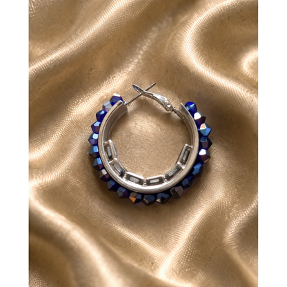 Blue crystal beaded hoop earring on gold satin fabric close up