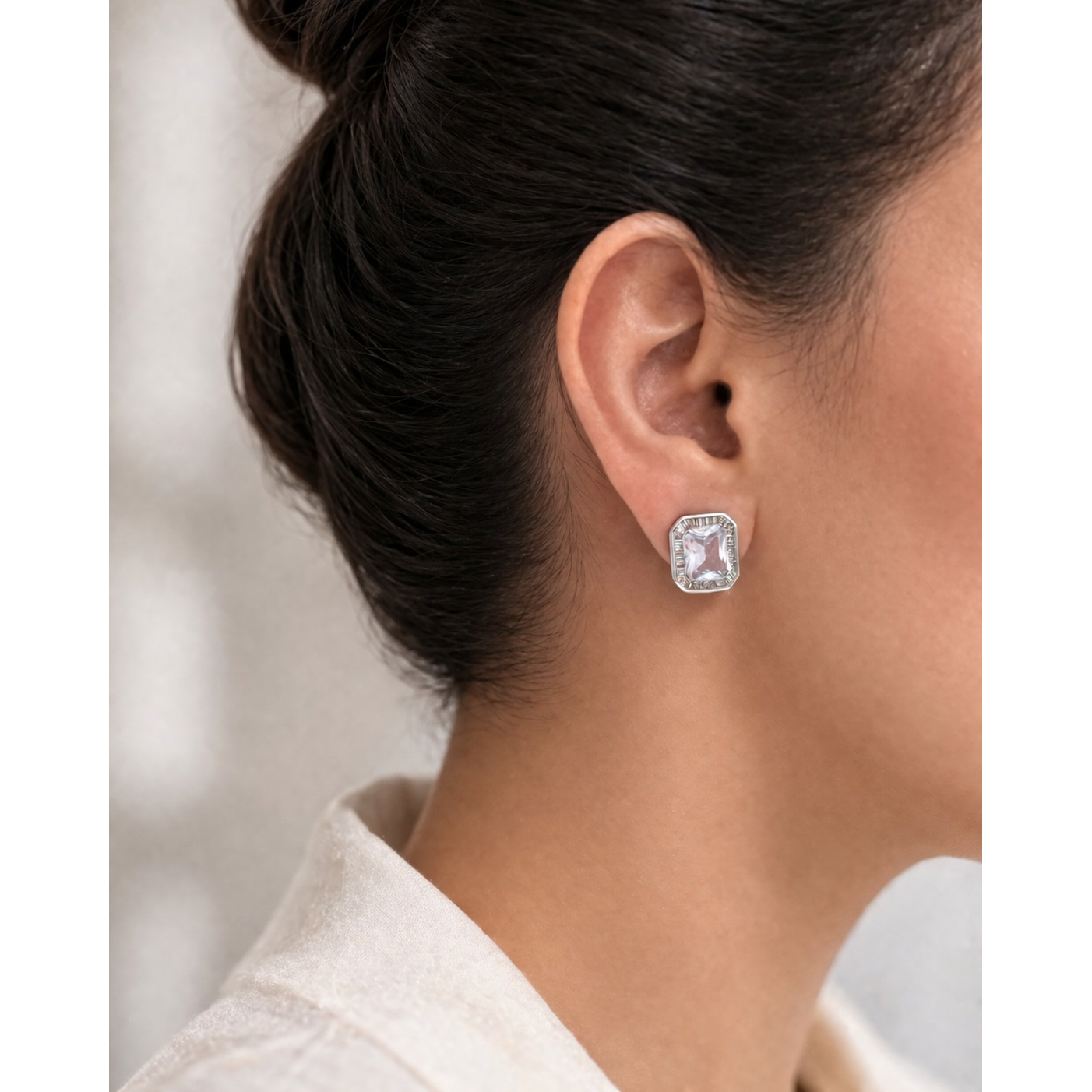Silver emerald-cut crystal stud earring worn on ear with soft natural lighting and clean background