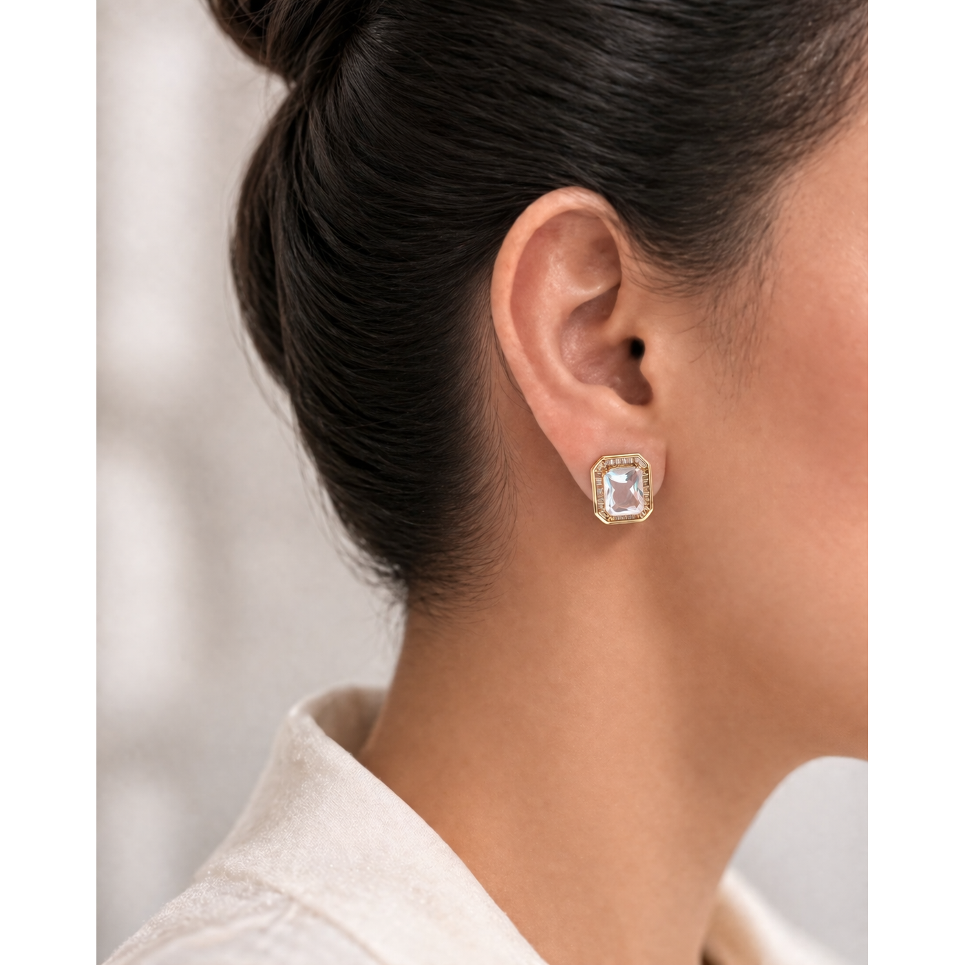 Gold emerald-cut crystal stud earring worn on ear with soft natural lighting and clean background