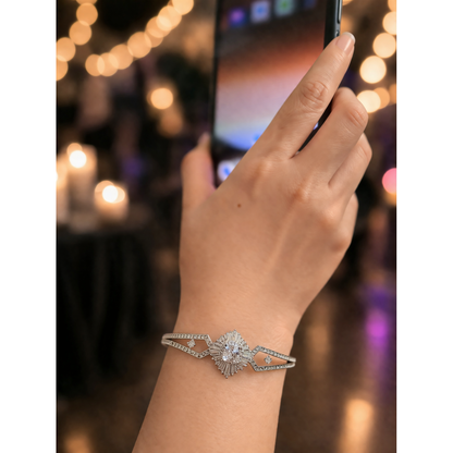 Silver crystal lock bracelet on hand with radiant center stone and geometric band design in soft party lighting
