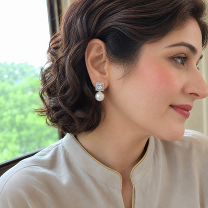 Woman wearing silver square zircon and white pearl drop statement earrings