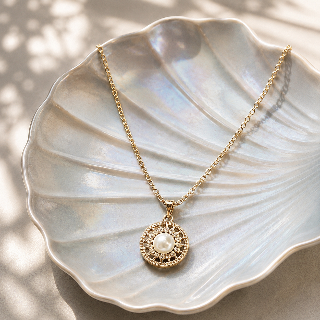 Solenne Pearl Pendant displayed on a pearlescent shell plate, featuring a round pearl centre with clear zircon accents and intricate openwork detailing.