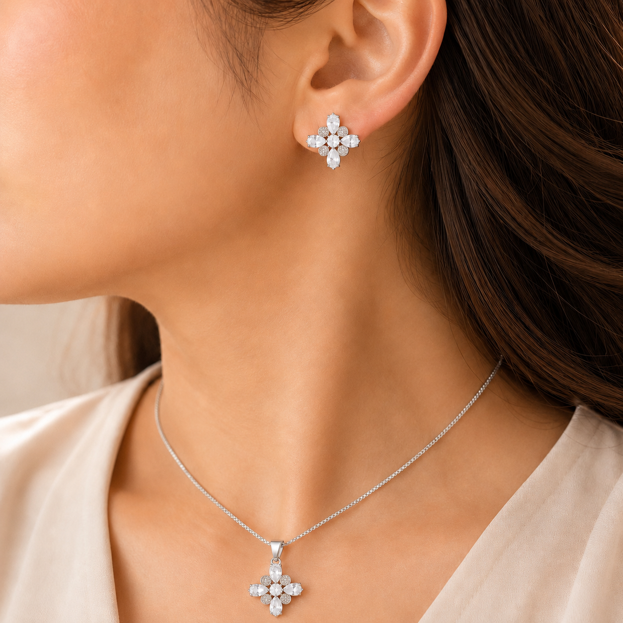 Woman wearing a silver-tone clear stone pendant necklace with matching four-point statement earrings.