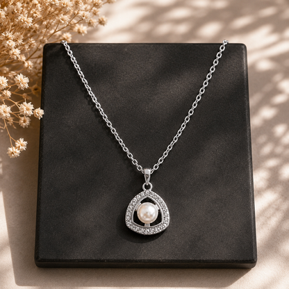 Pearl Axis silver-tone pendant with open triangular frame and clear stone detailing displayed on a black square plate.