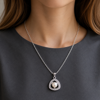 Silver-tone triangular pendant with luminous pearl centre and clear stone border worn on a fine chain.