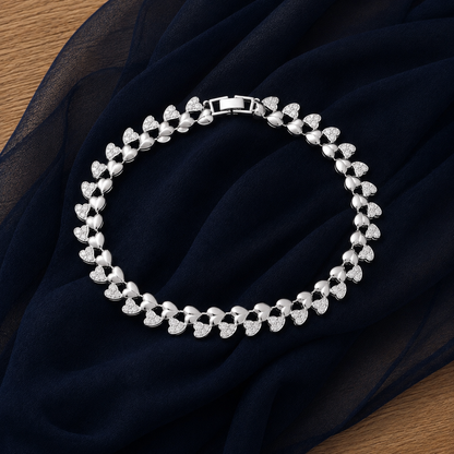 Silver-tone Twinheart Line Bracelet with alternating polished and clear stone-set heart links displayed on navy chiffon.