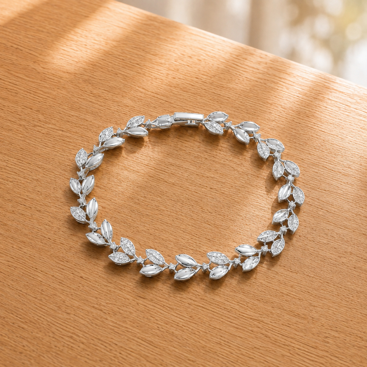 Silver leaf-link bracelet displayed in a circular arrangement on a light oakwood surface, highlighting its polished and zircon-detailed design.
