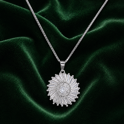 Silver Solar Halo Pendant with clear centre zircon and radiating baguette-cut zircons displayed on deep forest green velvet.