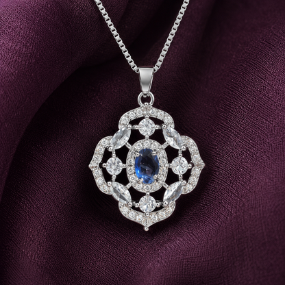 Close-up of intricate silver locket featuring a blue oval centre stone, marquise-cut clear accents and zircon-studded openwork detailing.