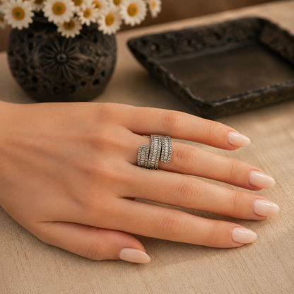 S925 sterling silver wrap ring with baguette and pavé zircon stones worn on a hand with soft nude nails, photographed in a luxury lifestyle setting.