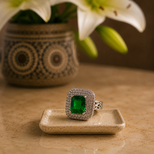Emerald green cushion-cut S925 statement ring displayed on a beige ceramic tray with soft luxury styling 
