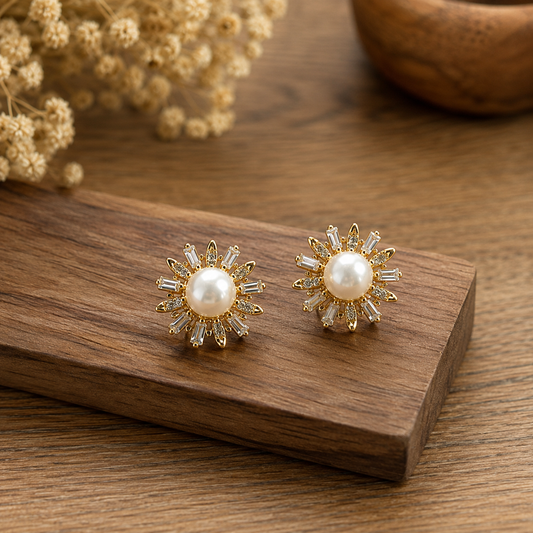 Pearl sunray stud earrings displayed on a wooden block with dried florals in a warm luxury setting.