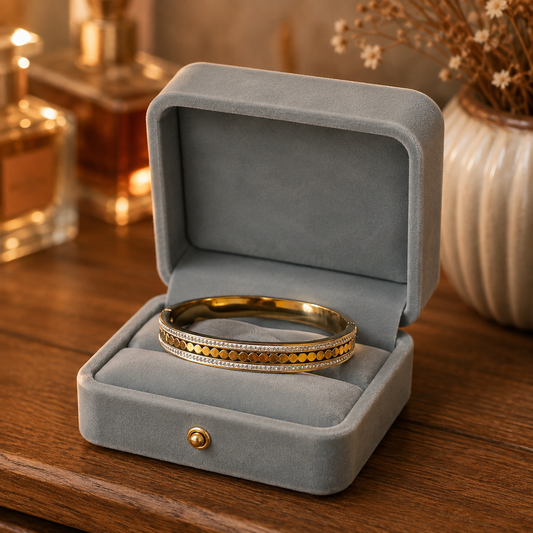 Gold-tone open cuff bracelet with crystal rows displayed inside a premium smoky light blue velvet bracelet box.