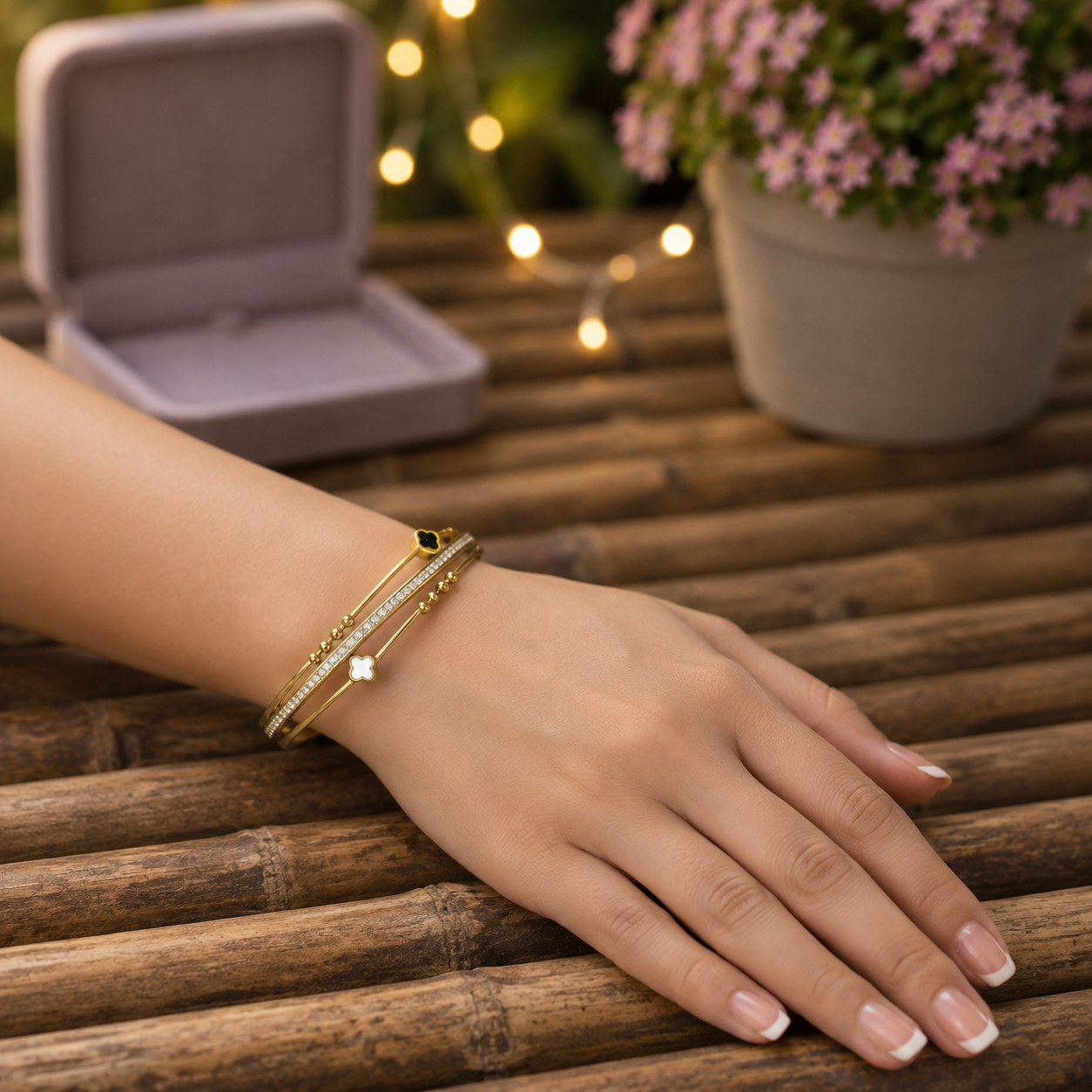Premium gold clover bracelet styled on a hand with a warm wooden background and soft fairy lights.