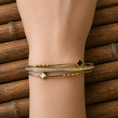 Close-up of a gold clover lock bracelet worn on the wrist with sparkling zircon detailing.