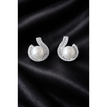 Luxury TIAS silver pearl stud earrings with sparkling crystal accents placed on fine black satin fabric.