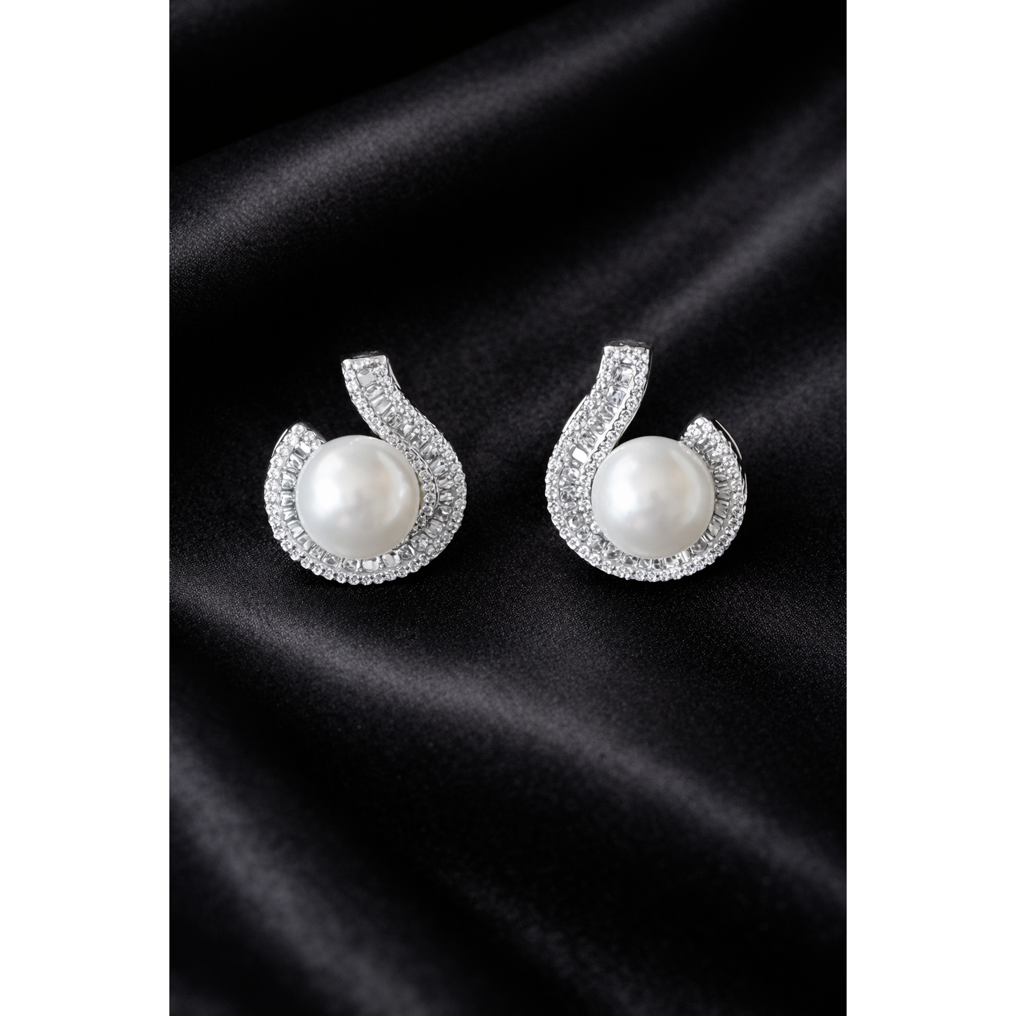 TIAS silver pearl stud earrings with crystal accents displayed on a black satin fabric