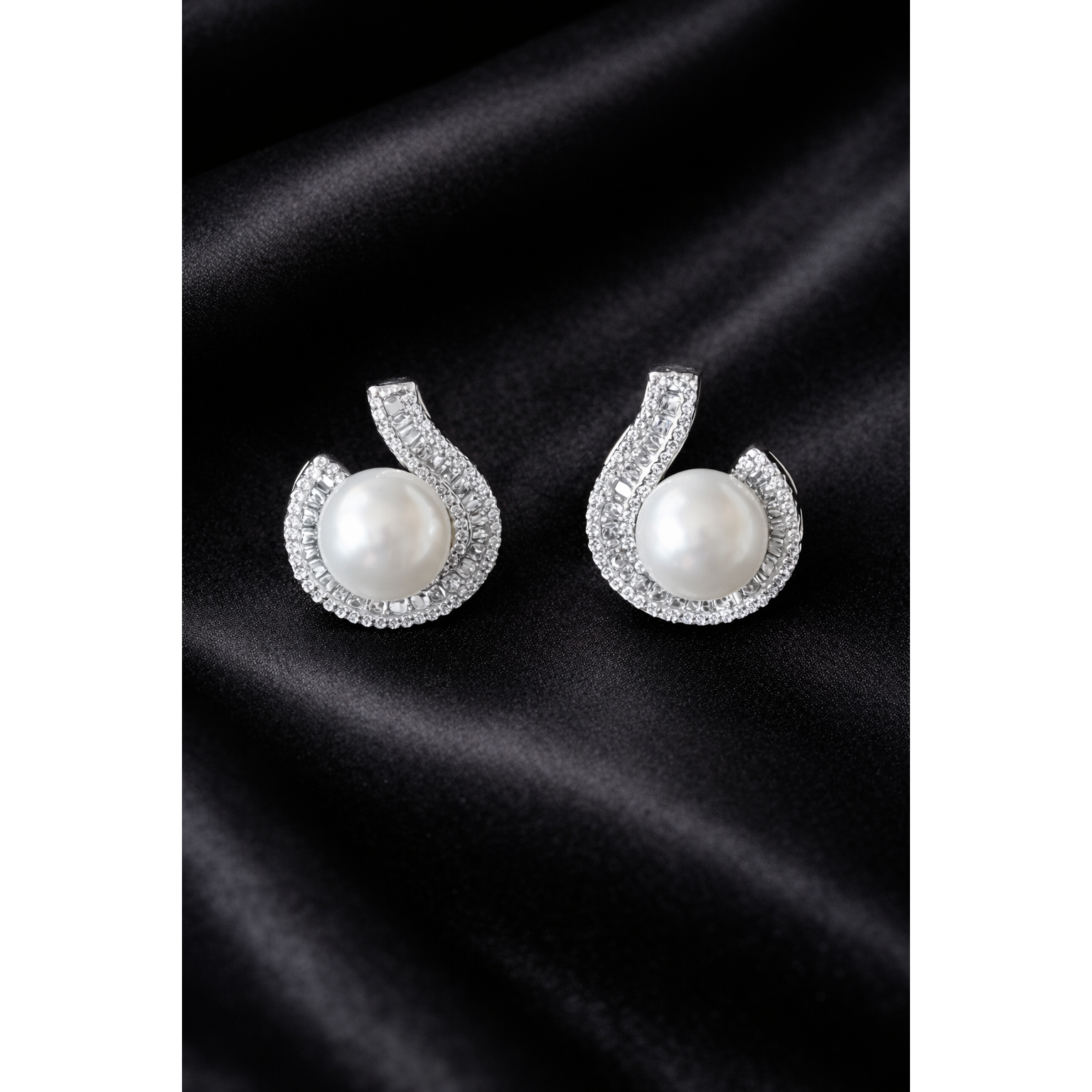 TIAS silver pearl stud earrings with crystal accents displayed on a black satin fabric