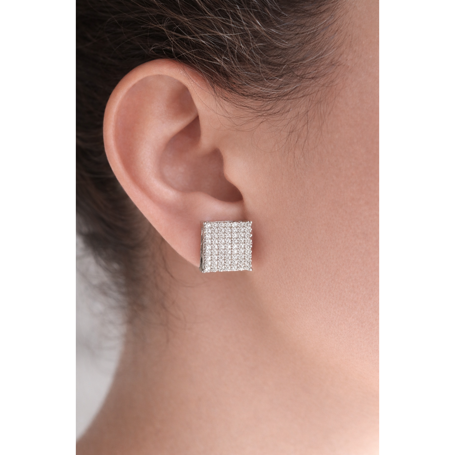 Luxury close-up of square pavé stud earrings worn on a model’s ear, highlighting size and brilliance