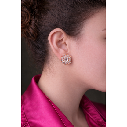 Light gold sunburst crystal stud earrings worn by model, featuring round center crystal and radiant baguette detailing in close-up fashion portrait.