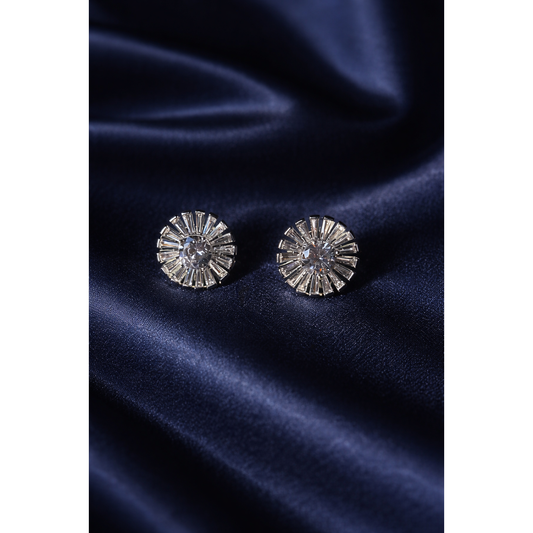 Silver sunburst crystal stud earrings with round center stone displayed on dark blue satin fabric in high-definition jewellery photography.