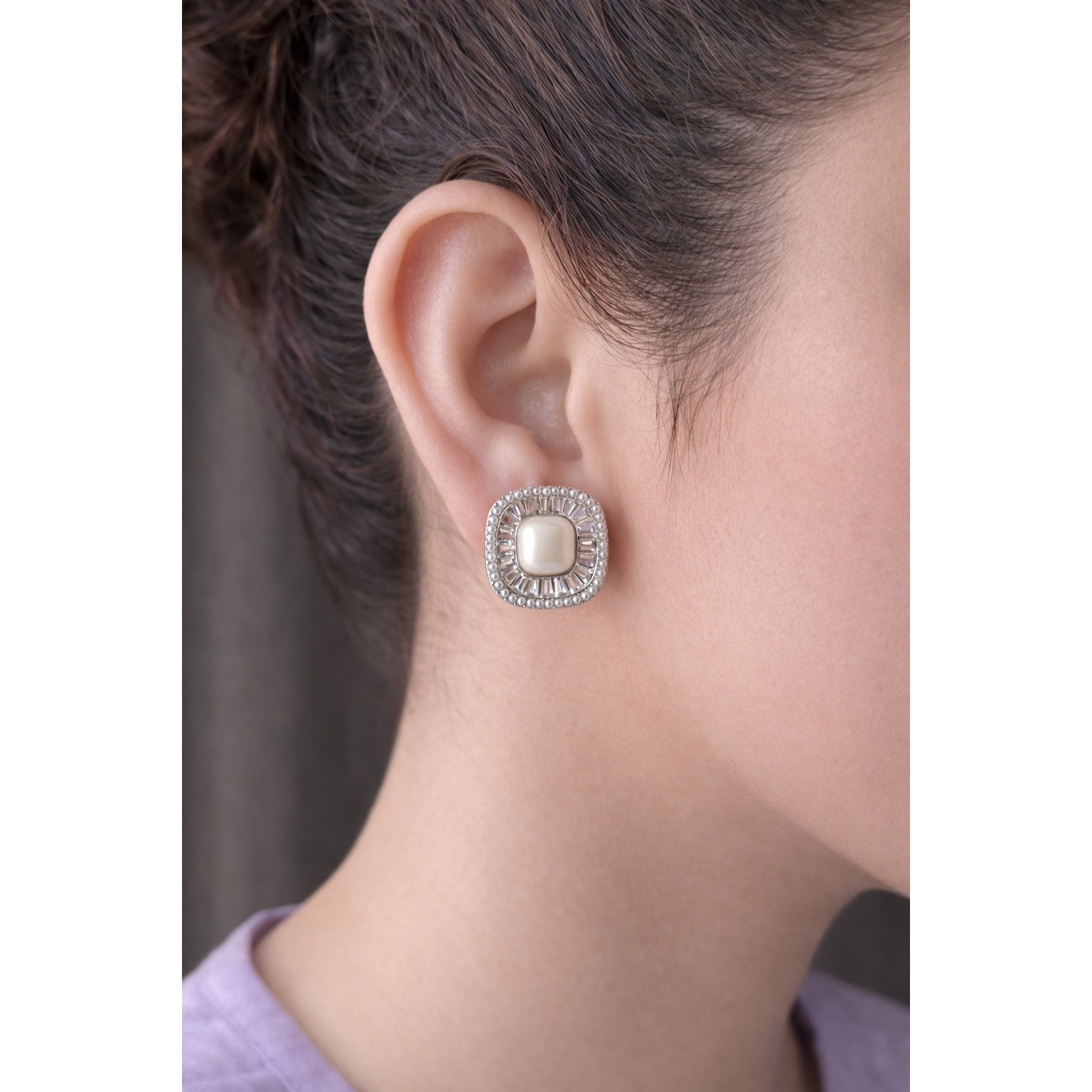 Model wearing square pearl halo stud earrings with crystal accents and pearl border, styled with soft lilac clothing in close-up portrait
