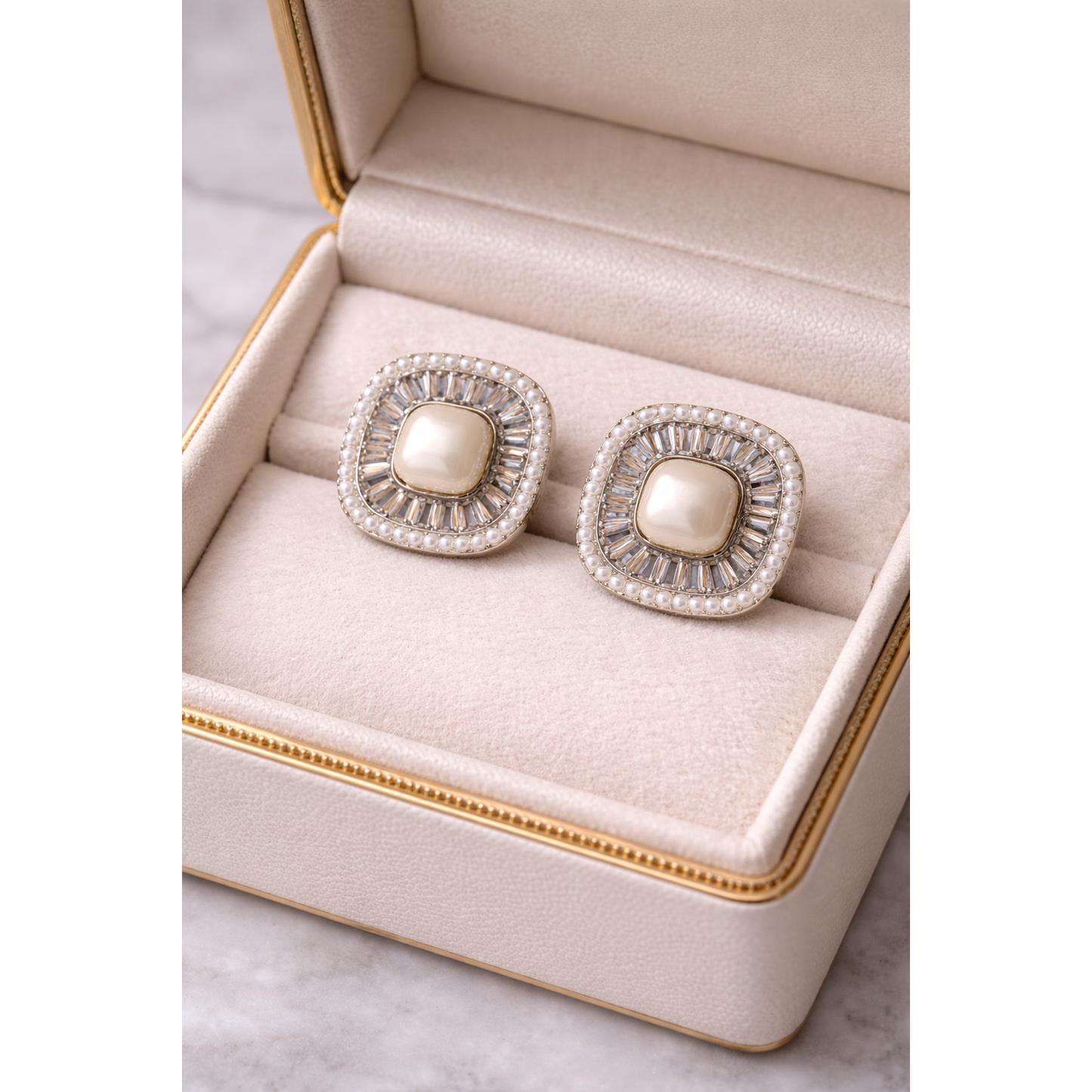 Close-up of square pearl statement stud earrings displayed inside a premium jewelry box with soft neutral lining