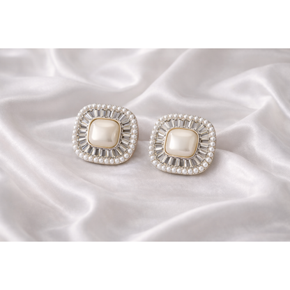 Square pearl halo stud earrings placed on white silk fabric showing crystal detailing and micro pearl border in high definition