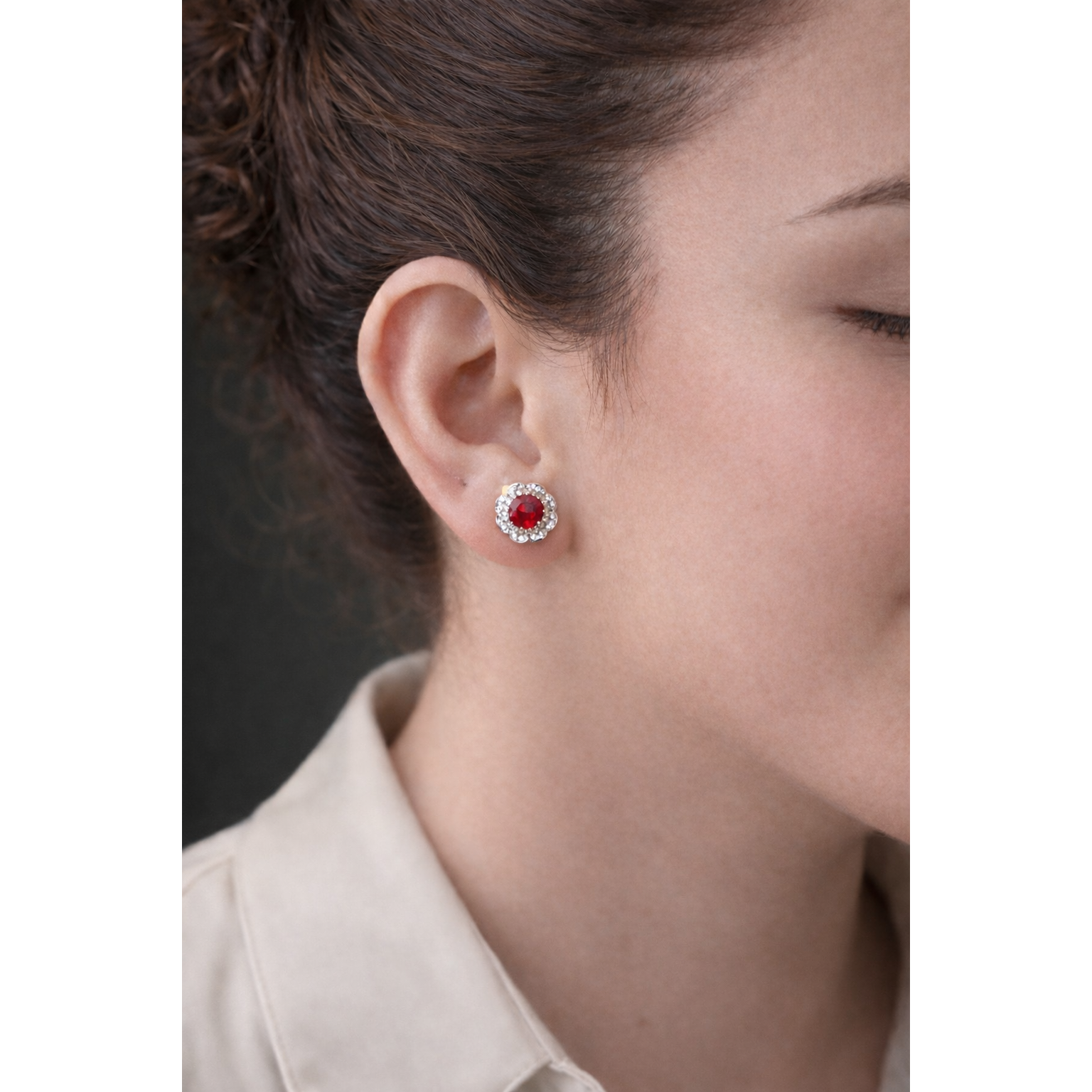 Side profile of woman wearing silver floral halo stud earrings with pinkish red centre crystal